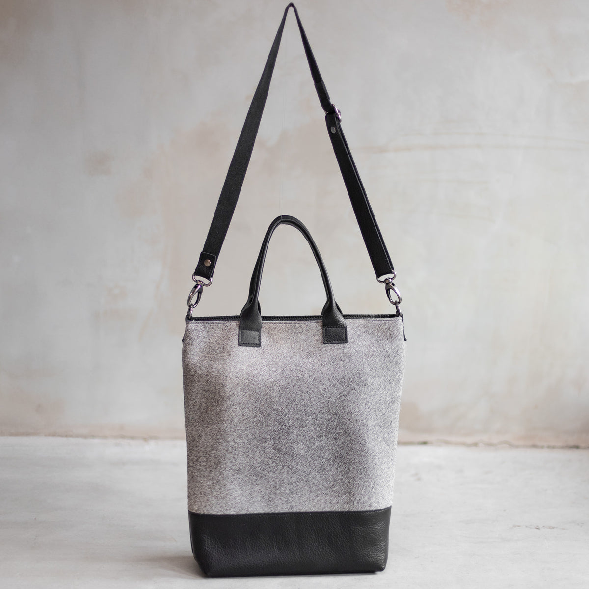Grand sac à main en cuir et peau de vache grise, vu de face avec sa bandoulière en cuir noir