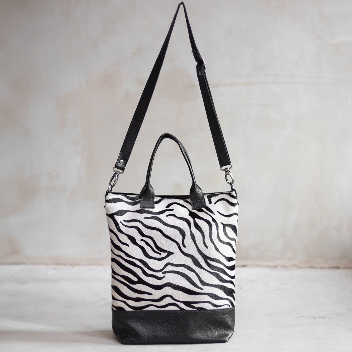 Grand sac à main en cuir et peau de vache zèbre, vu de face avec sa bandoulière en cuir noir
