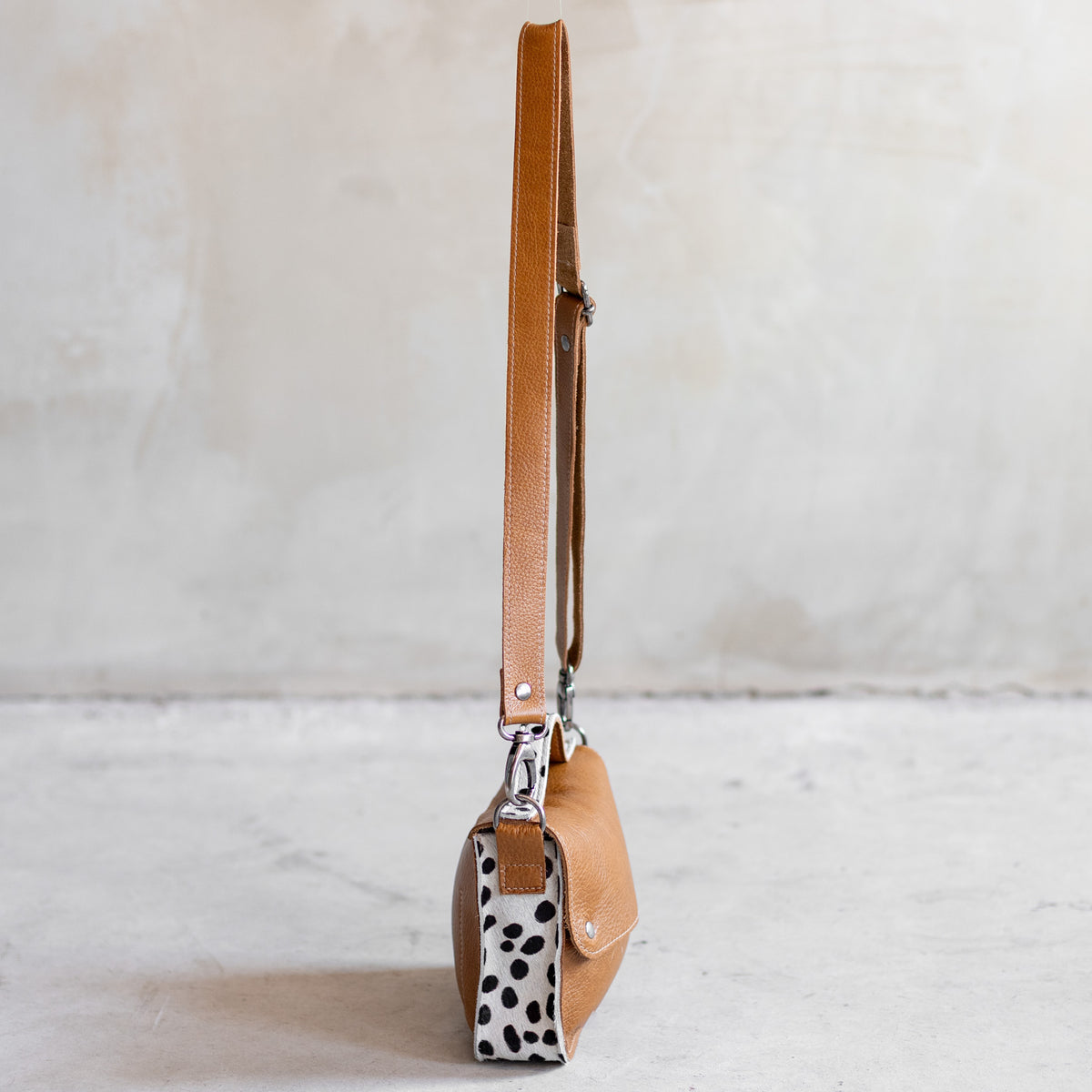 Petit sac à main bandoulière en cuir cognac et côtés dalmatien, vu de profil avec côté dalmatien