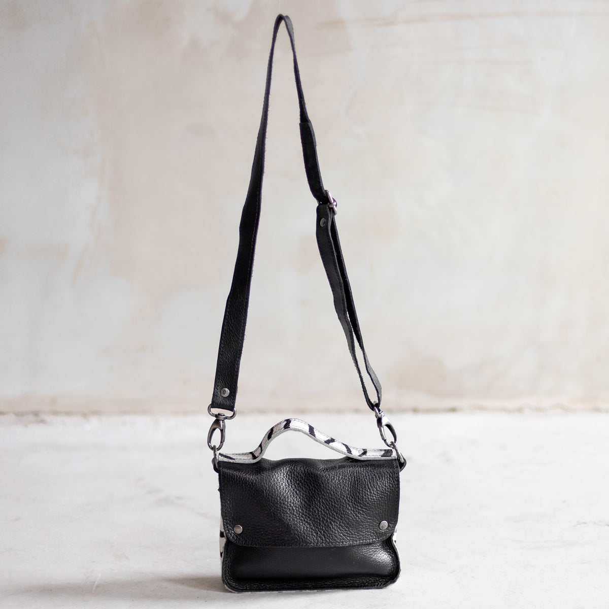 Petit sac à main bandoulière en cuir noir et côtés zèbre, vu de loin avec sa bandoulière
