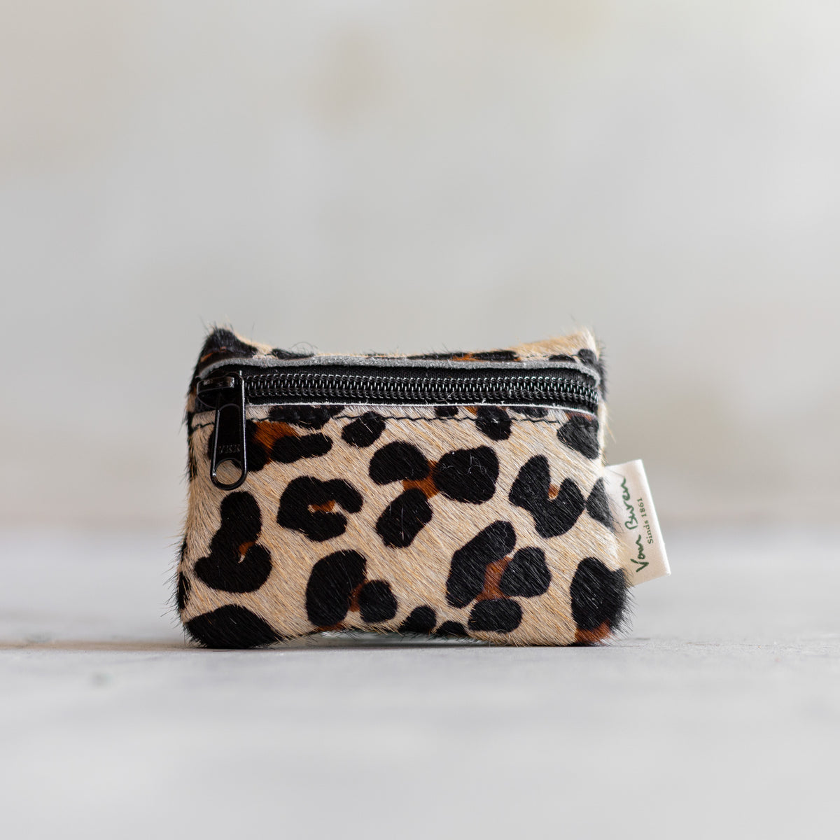 Porte-monnaie zippé en peau de vache léopard, vu de face, fermeture éclair