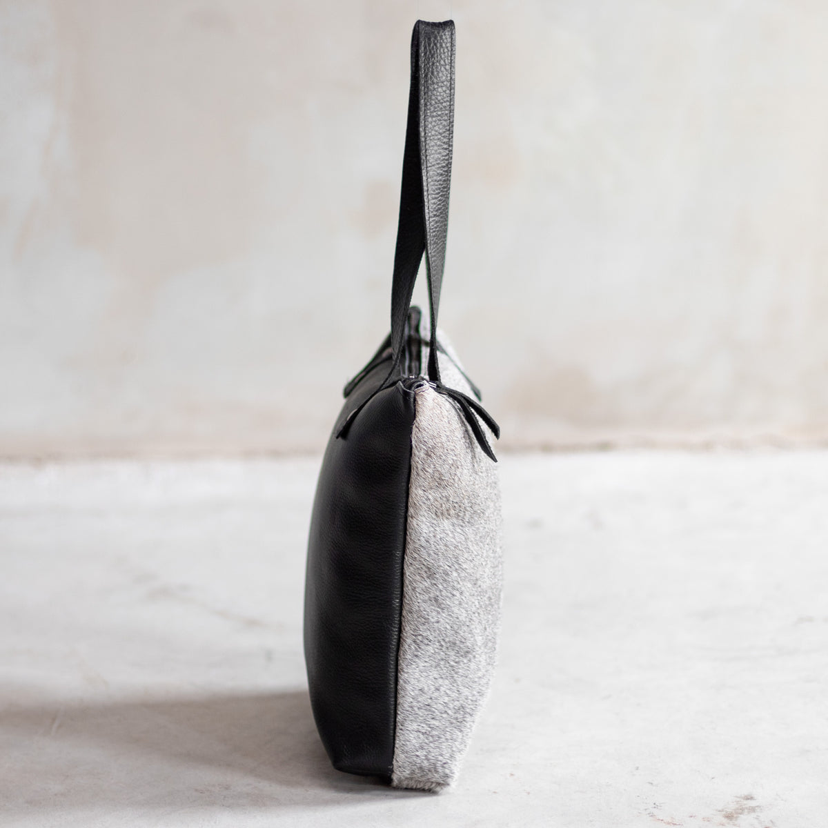 Sac à main épaule zippé en cuir et peau de vache grise, vu de profil