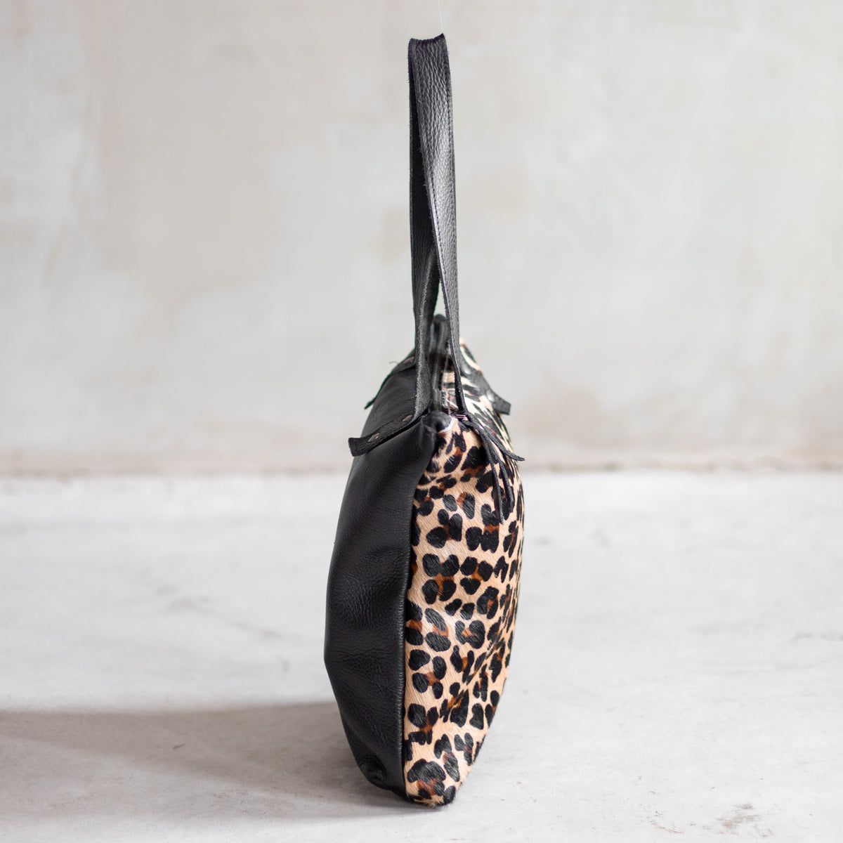Sac à main épaule zippé en cuir et peau de vache léopard, vu de profil