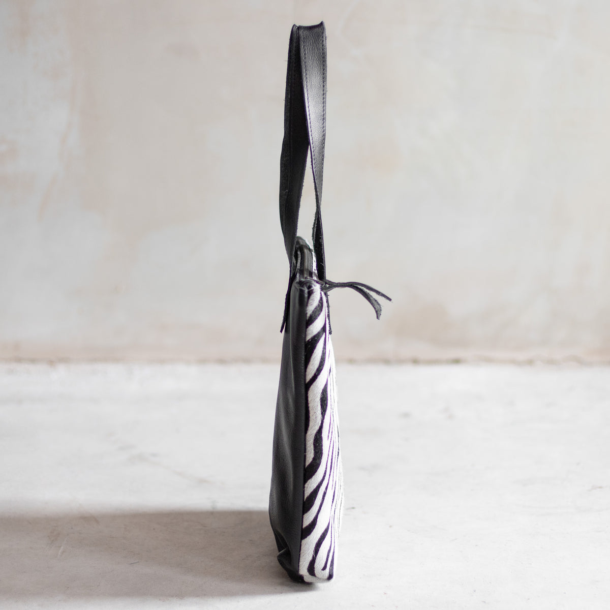 Sac à main épaule zippé en cuir et peau de vache zèbre, vu de profil