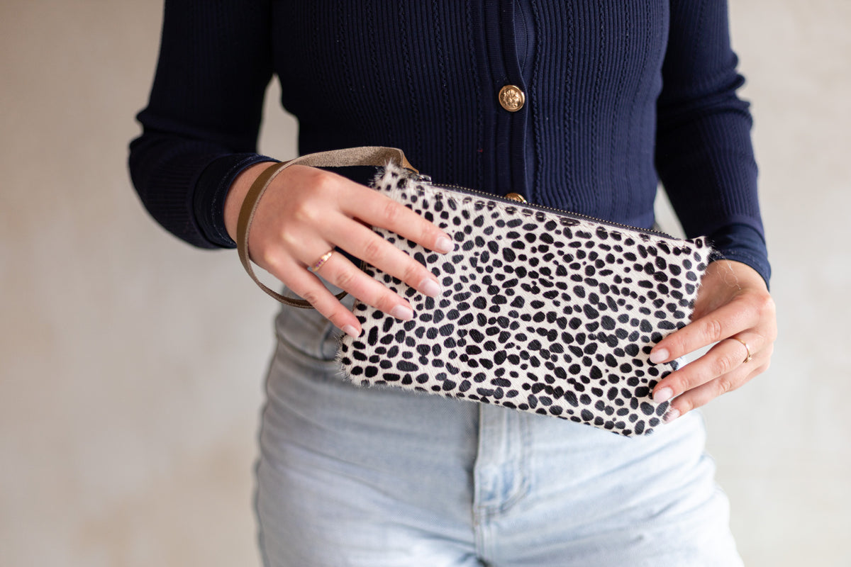 Sac à main pochette en peau de vache mini dalmatien, tenue à deux mains avec un jean