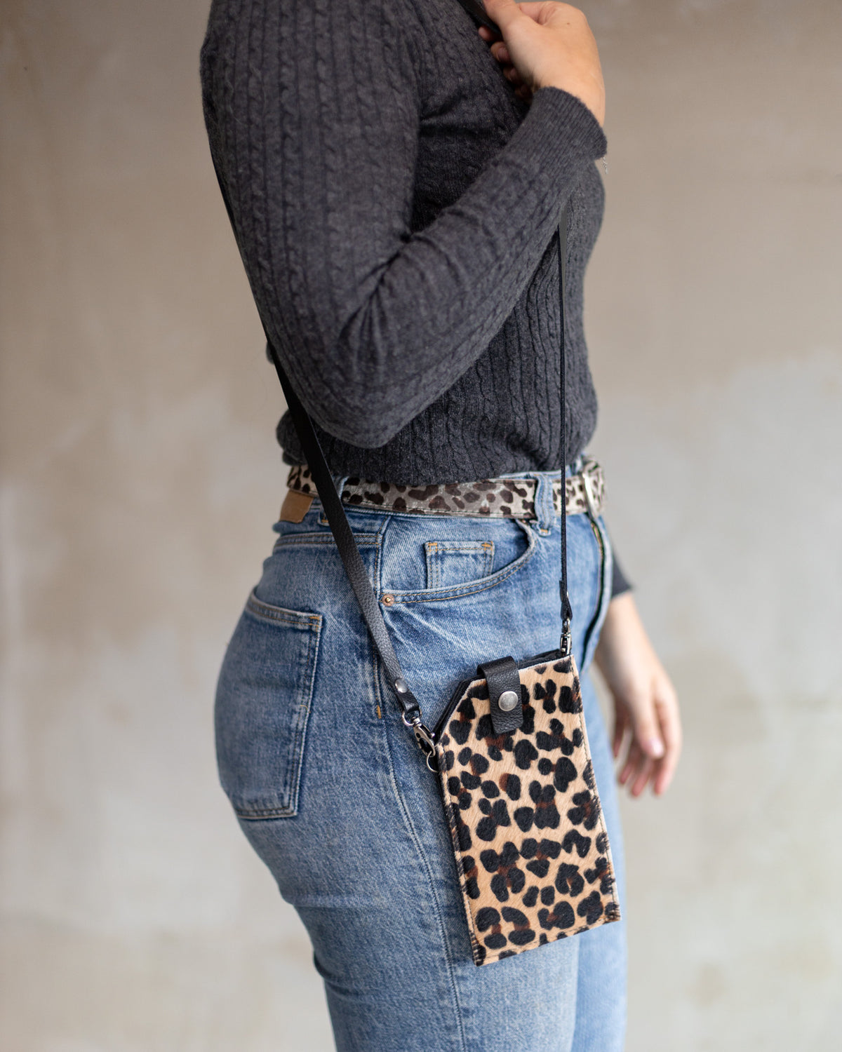Sac à main pochette téléphone en peau de vache léopard, portée en bandoulière avec un jean