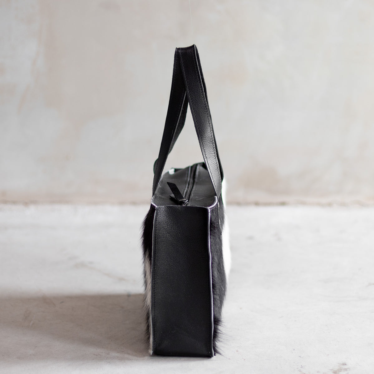 Sac à main rectangulaire en cuir noir et peau de vache noir et blanc, vu de profil