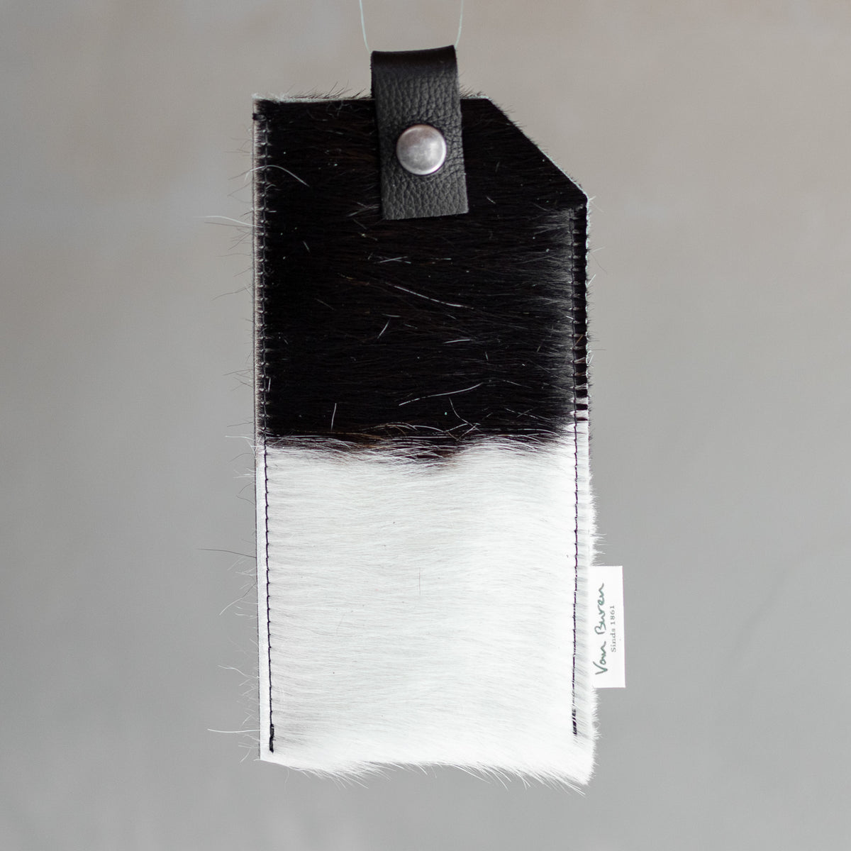 Étui à lunettes en peau de vache noir et blanc, vu de face, rabat à pression
