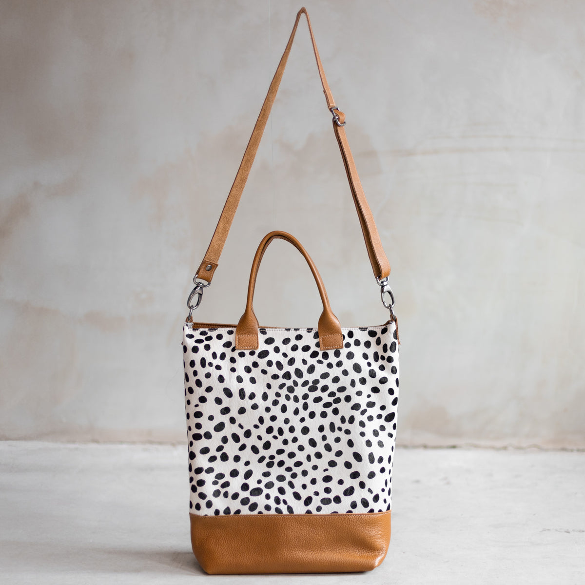 Grand sac à main en cuir et peau de vache dalmatien, vu de face avec sa bandoulière en cuir cognac