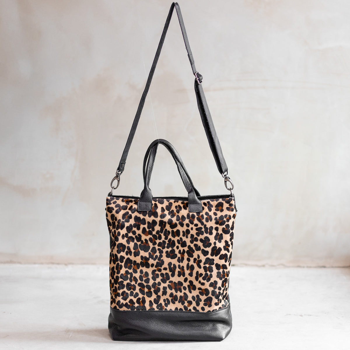 Grand sac à main en cuir et peau de vache léopard, vu de face avec sa bandoulière en cuir noir