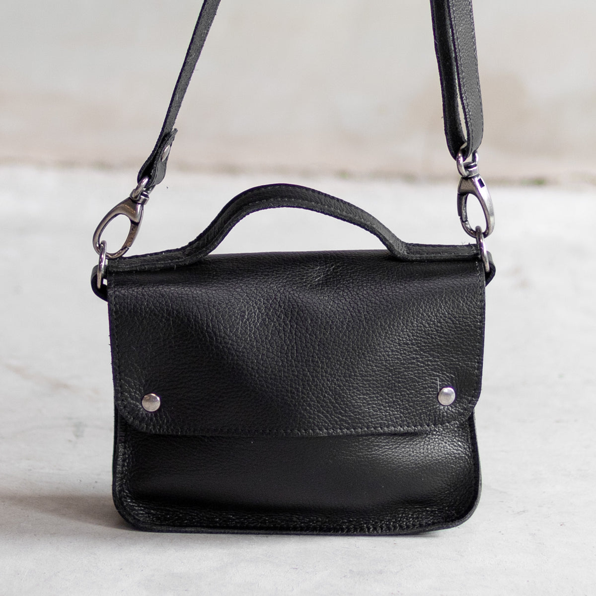 Petit sac à main bandoulière en cuir noir, vu de face avec poignée et bandoulière