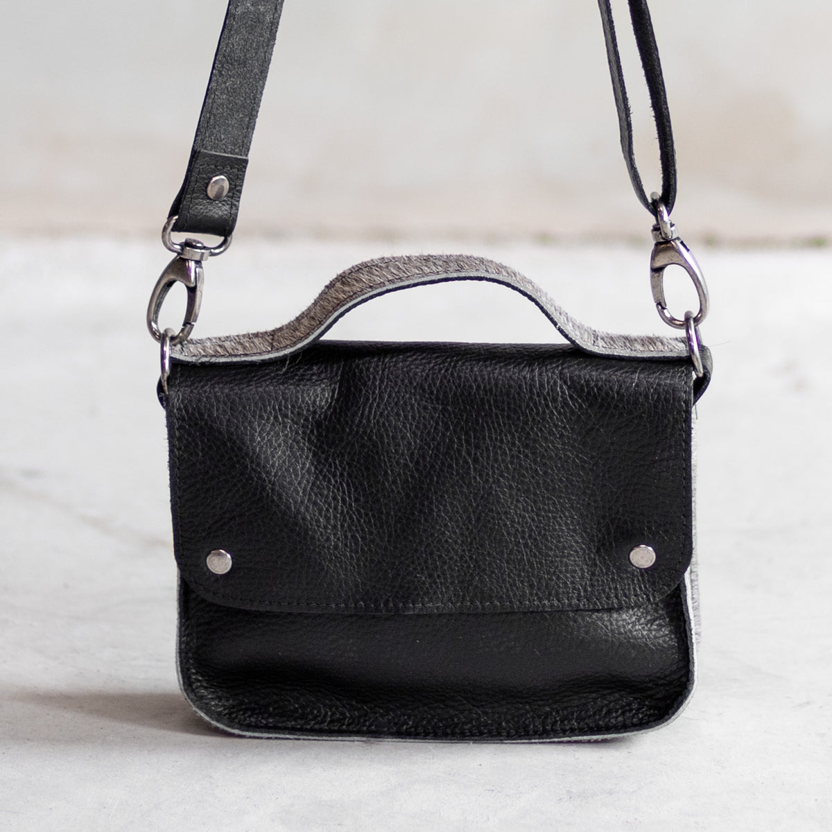 Petit sac à main bandoulière en cuir noir et côtés gris, vu de face, poignée en peau de vache grise