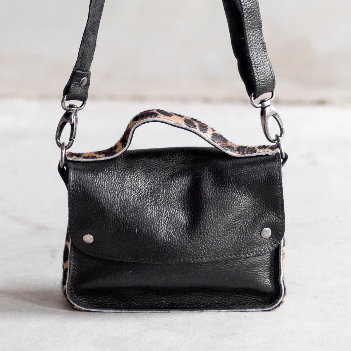 Petit sac à main bandoulière en cuir noir et côtés léopard, vu de face, poignée léopard