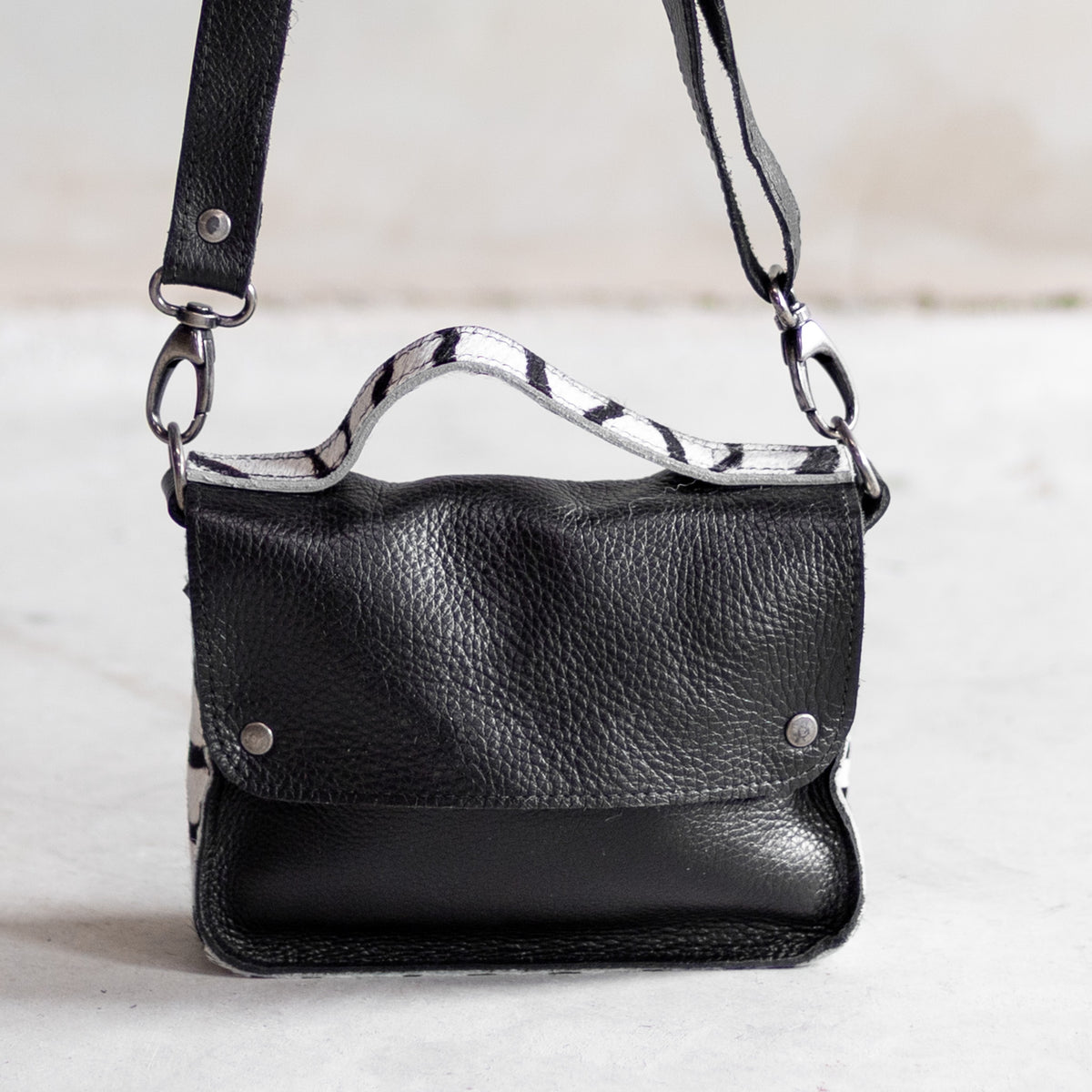 Petit sac à main bandoulière en cuir noir et côtés zèbre, vu de face, poignée zébrée