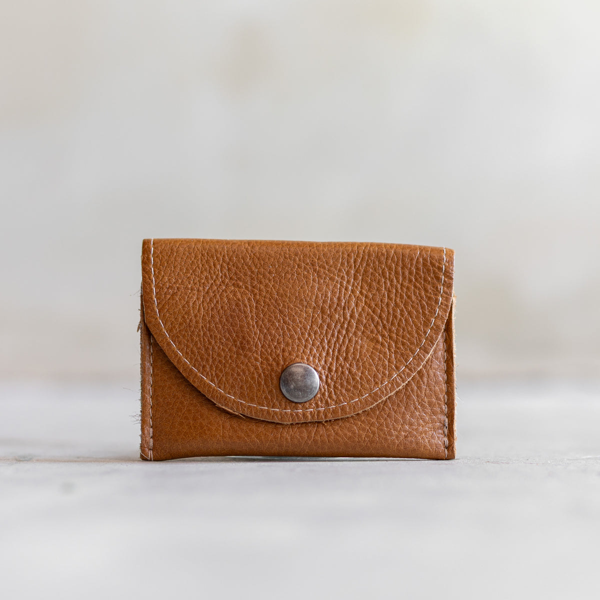 Porte-monnaie en cuir cognac, vu de face, rabat arrondi à pression