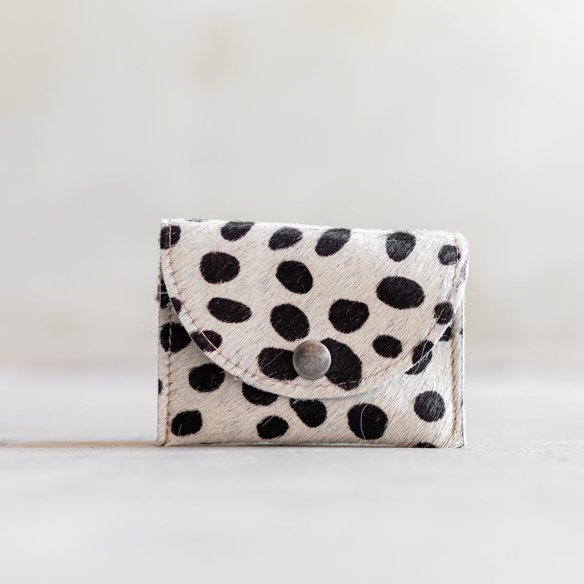 Porte-monnaie en peau de vache dalmatien, vu de face, rabat arrondi à pression