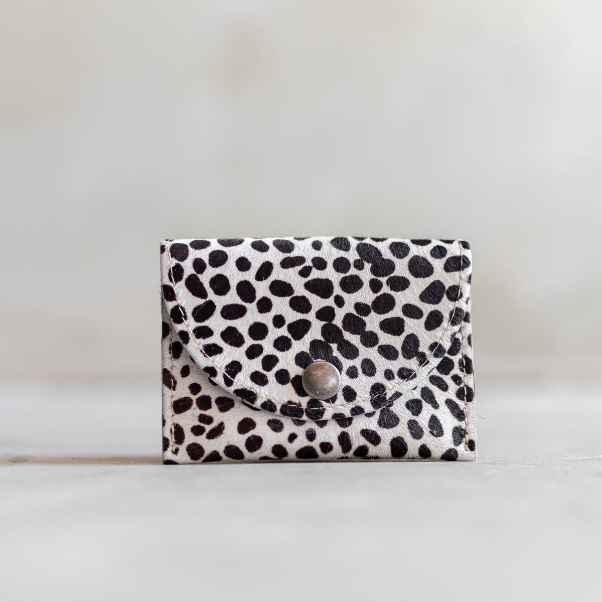 Porte-monnaie en peau de vache mini dalmatien, vu de face, rabat arrondi à pression