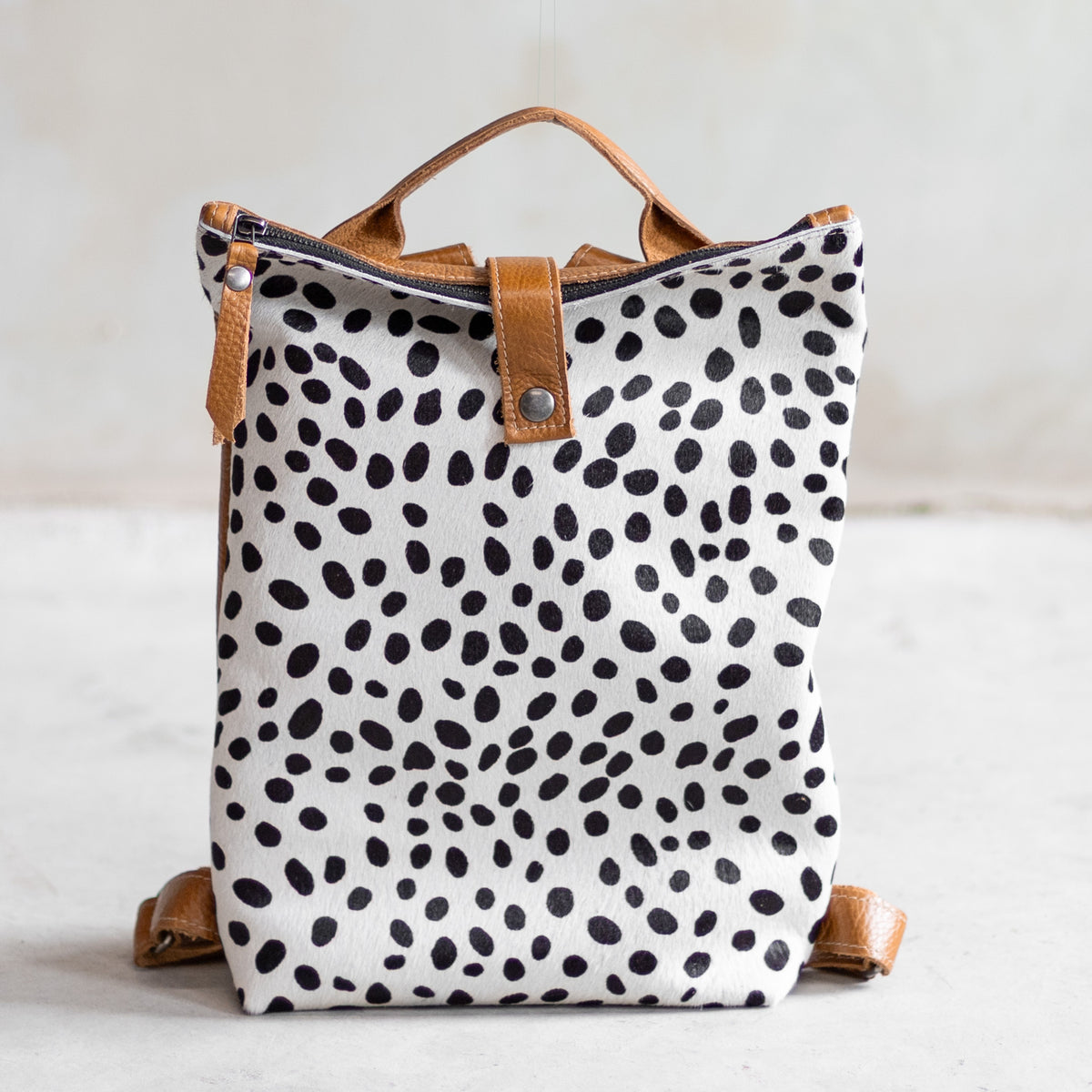 Sac à main à dos en cuir et peau de vache dalmatien, vu de face, poignée en cuir cognac