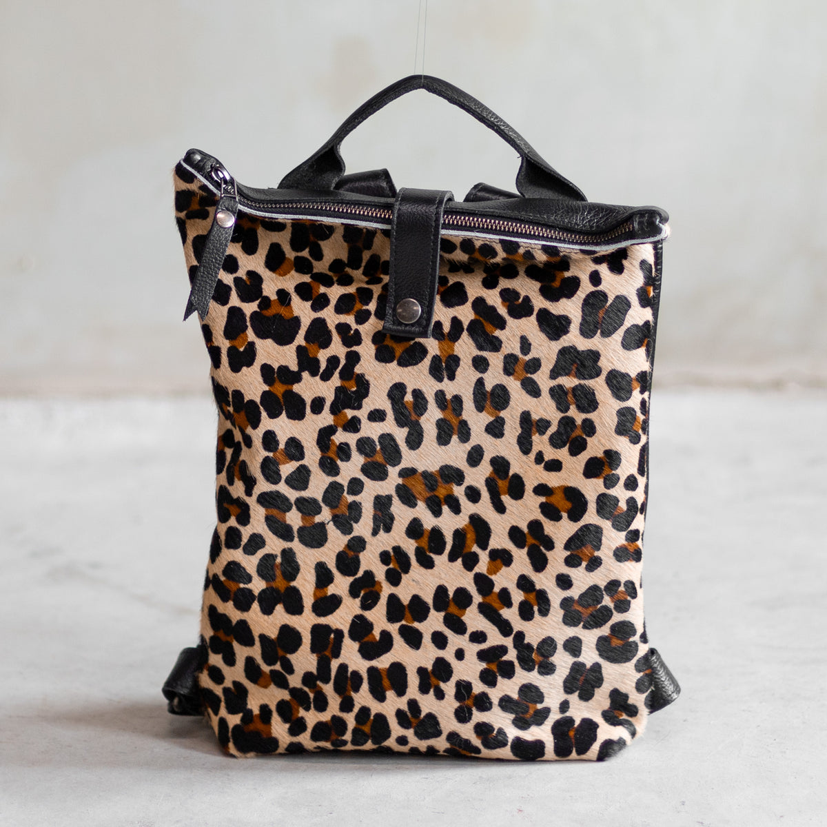 Sac à main à dos en cuir et peau de vache léopard, vu de face, poignée en cuir noir