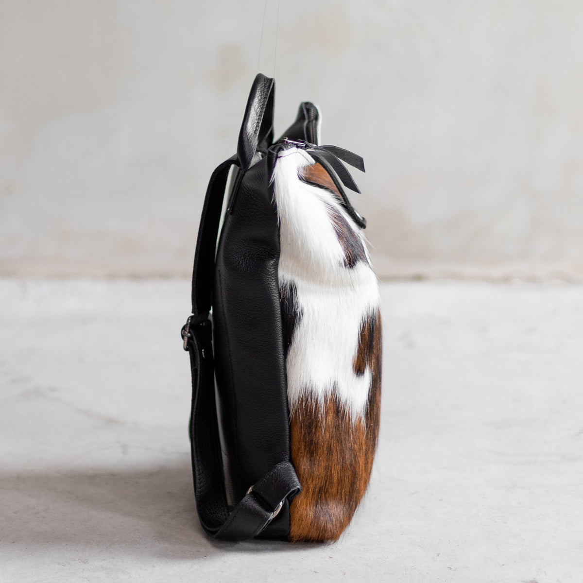 Sac à main à dos en cuir et peau de vache tricolore, vu de profil