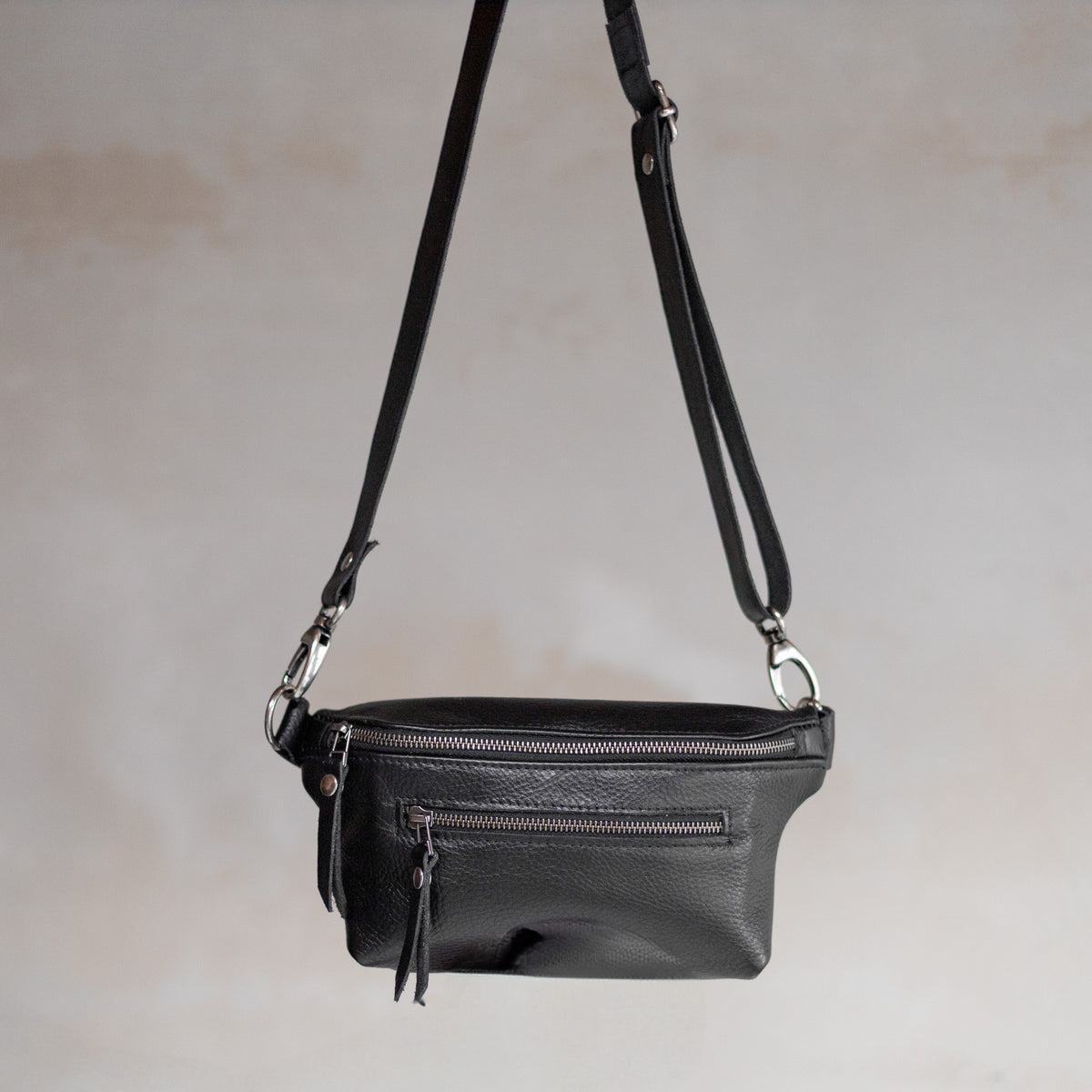 Sac à main banane en cuir noir, vu de face avec sa sangle en cuir