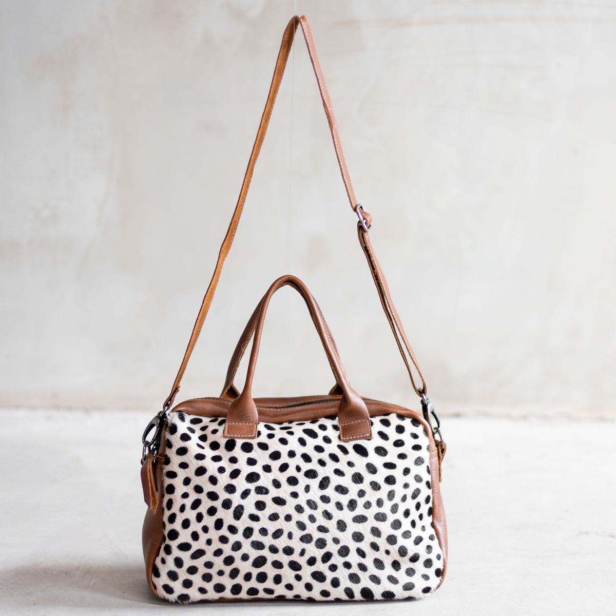Sac à main bowling en cuir cognac et peau de vache dalmatien, façade dalmatien vue de face avec bandoulière
