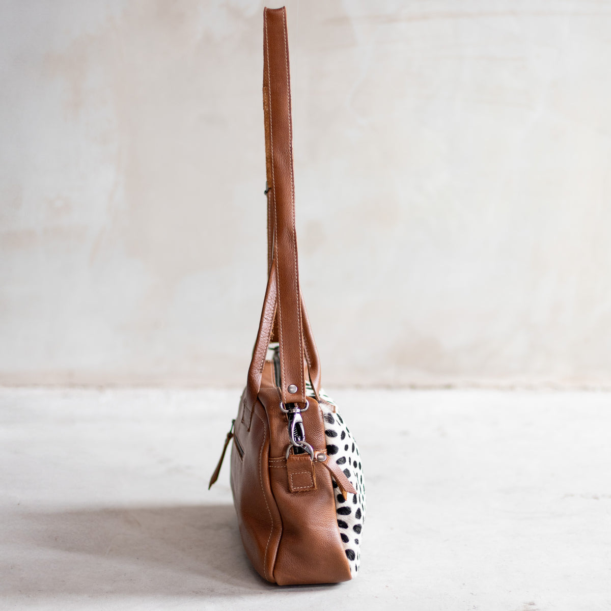 Sac à main bowling en cuir cognac et peau de vache dalmatien, vu de profil