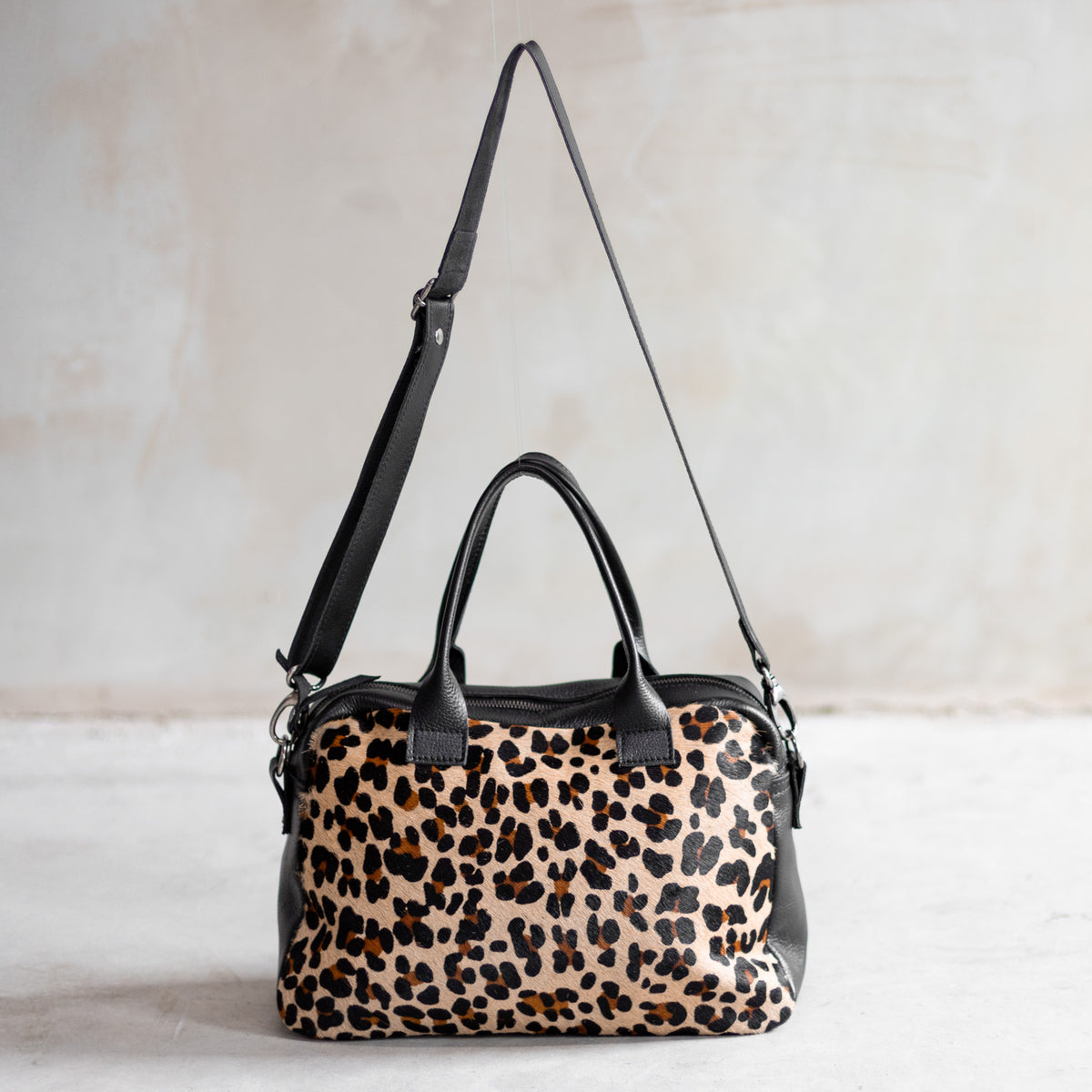 Sac à main bowling en cuir noir et peau de vache léopard, façade léopard vue de face avec bandoulière