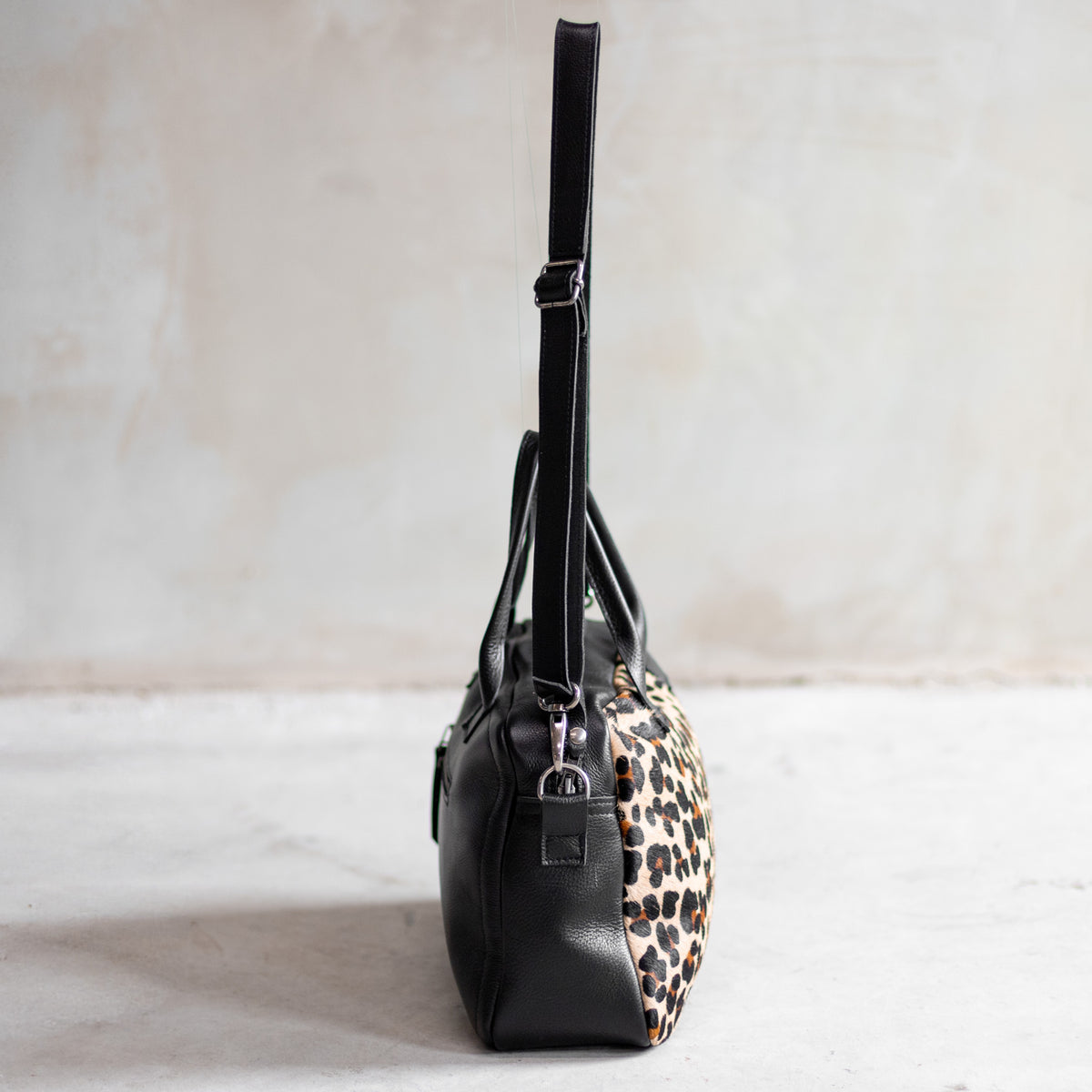 Sac à main bowling en cuir noir et peau de vache léopard, vu de profil