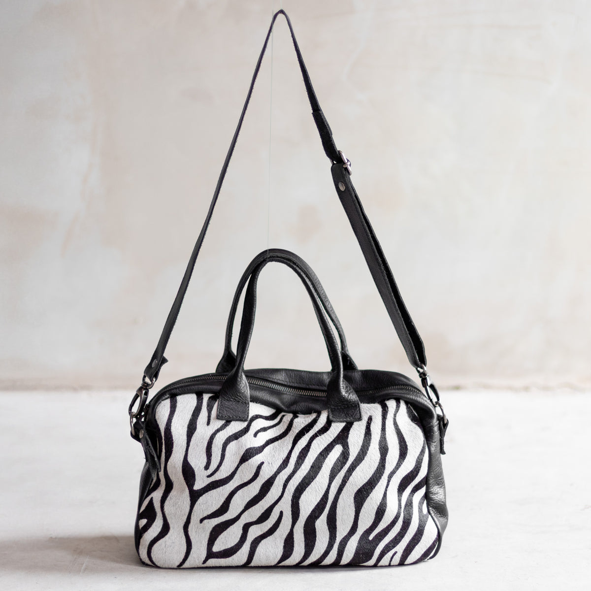 Sac à main bowling en cuir noir et peau de vache zèbre, façade zébrée vue de face avec bandoulière