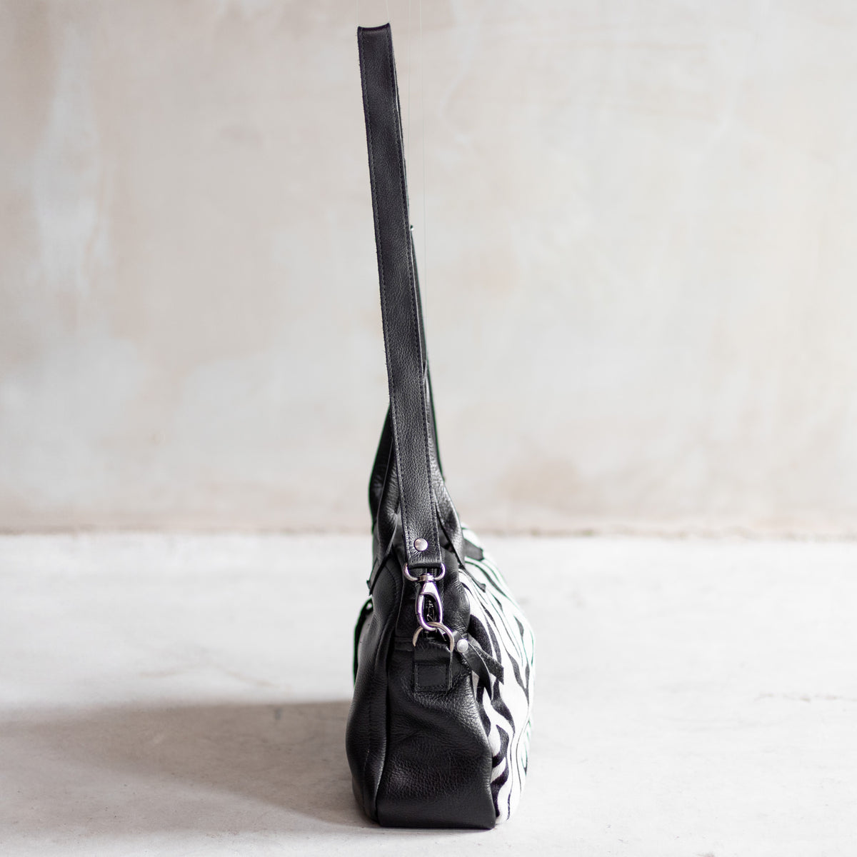 Sac à main bowling en cuir noir et peau de vache zèbre, vu de profil