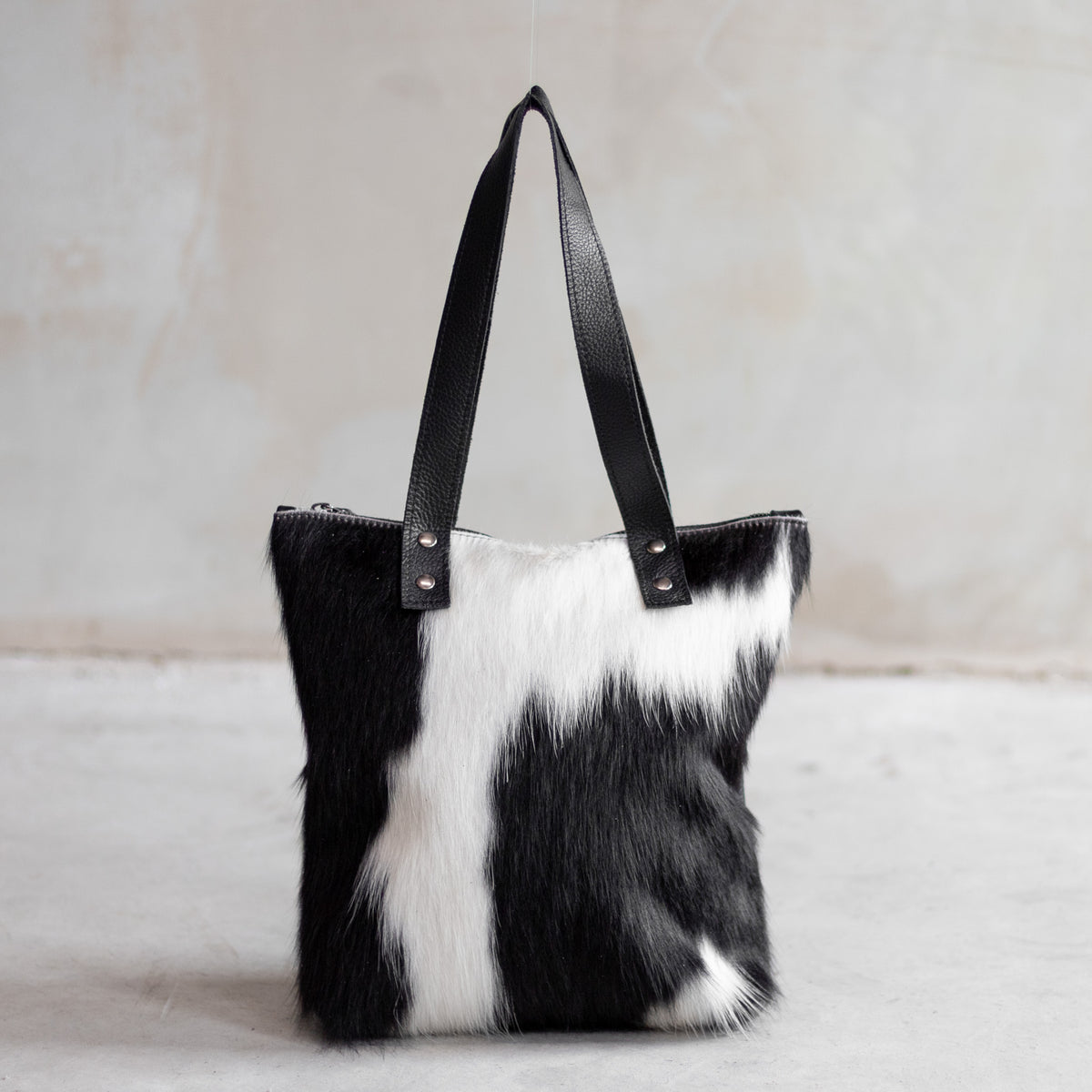 Sac à main épaule zippé en cuir et peau de vache noir et blanc, façade noir et blanc vue de face