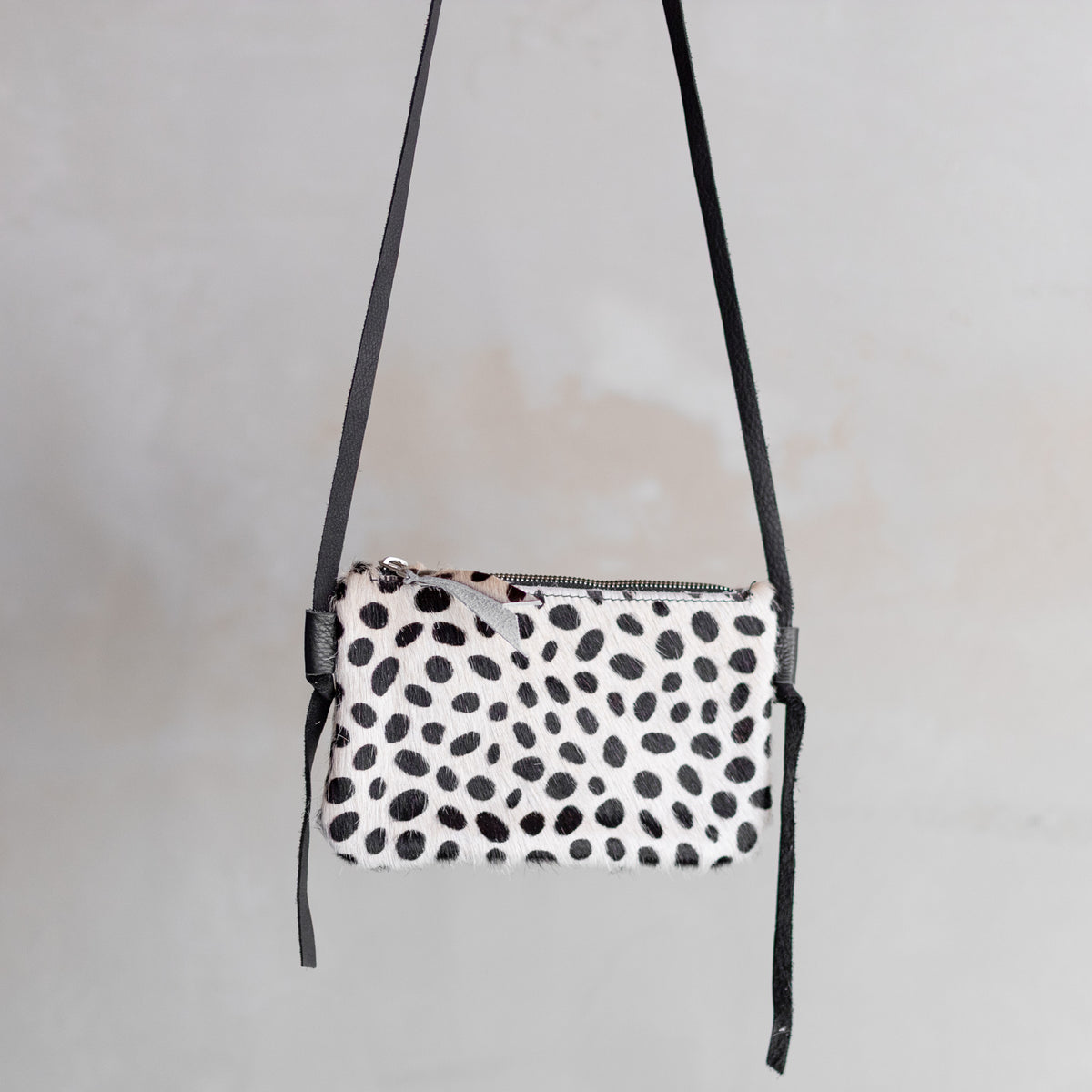 Sac à main pochette bandoulière en peau de vache dalmatien, suspendue par sa bandoulière
