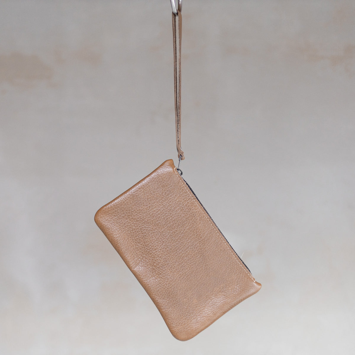 Sac à main pochette en cuir sable, suspendue par sa dragonne