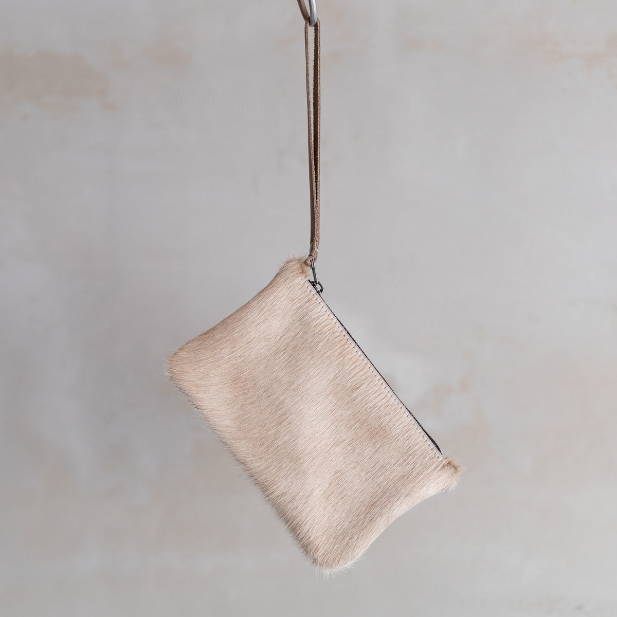 Sac à main pochette en peau de vache crème, suspendue par sa dragonne