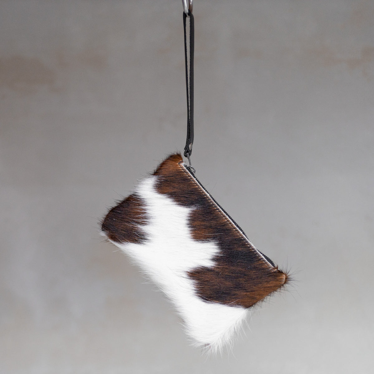 Sac à main pochette en peau de vache tricolore, suspendue par sa dragonne