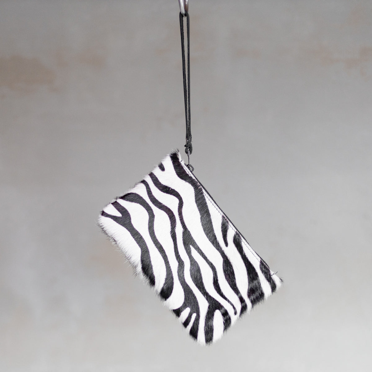 Sac à main pochette en peau de vache zèbre, suspendue par sa dragonne