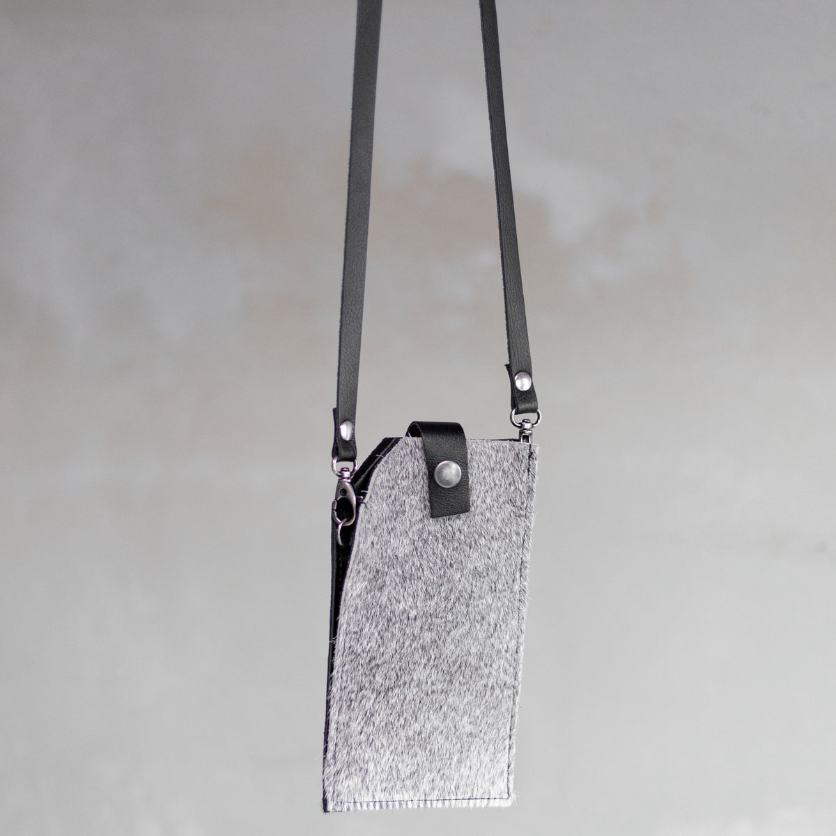 Sac à main pochette téléphone en peau de vache grise, suspendue par sa bandoulière