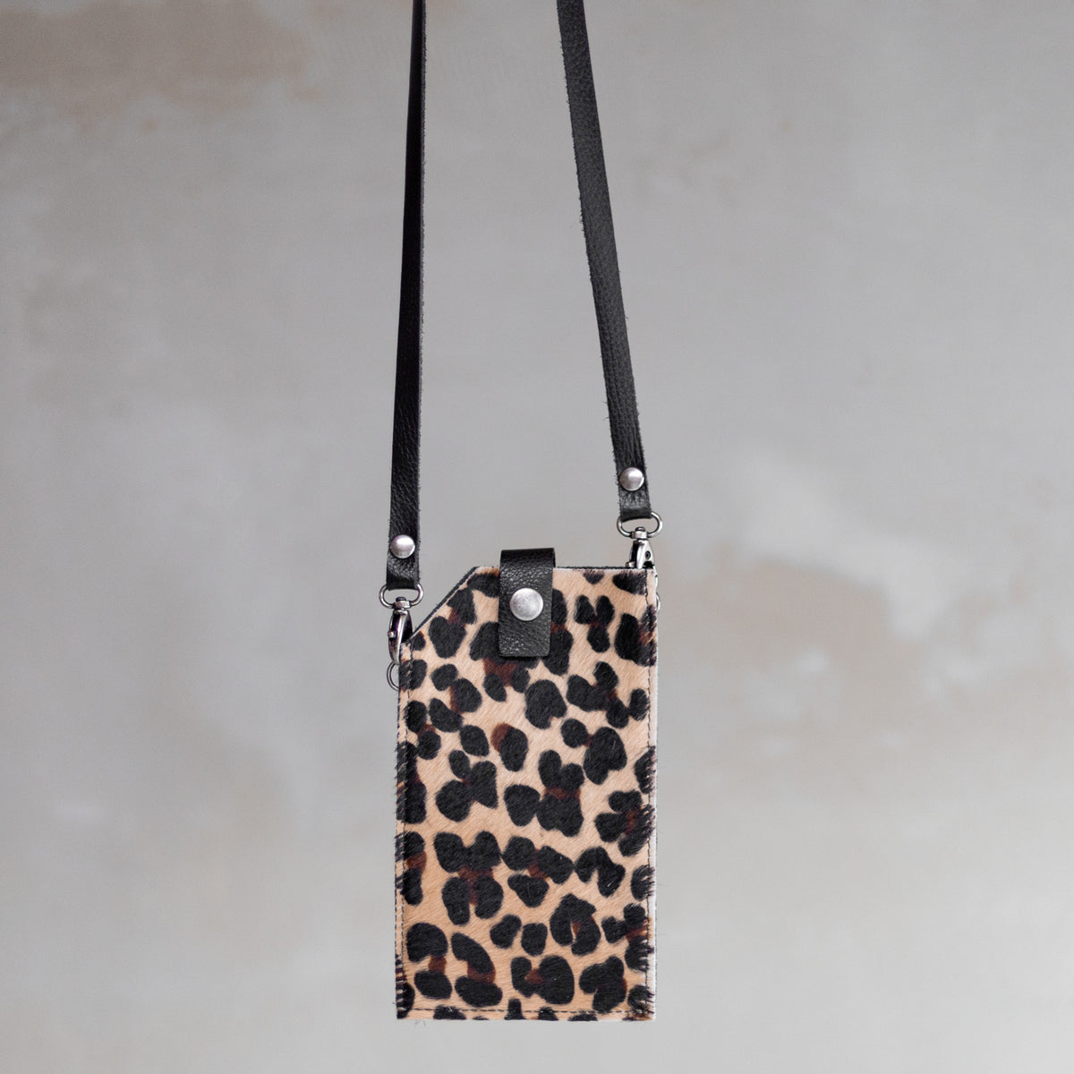 Sac à main pochette téléphone en peau de vache léopard, suspendue par sa bandoulière