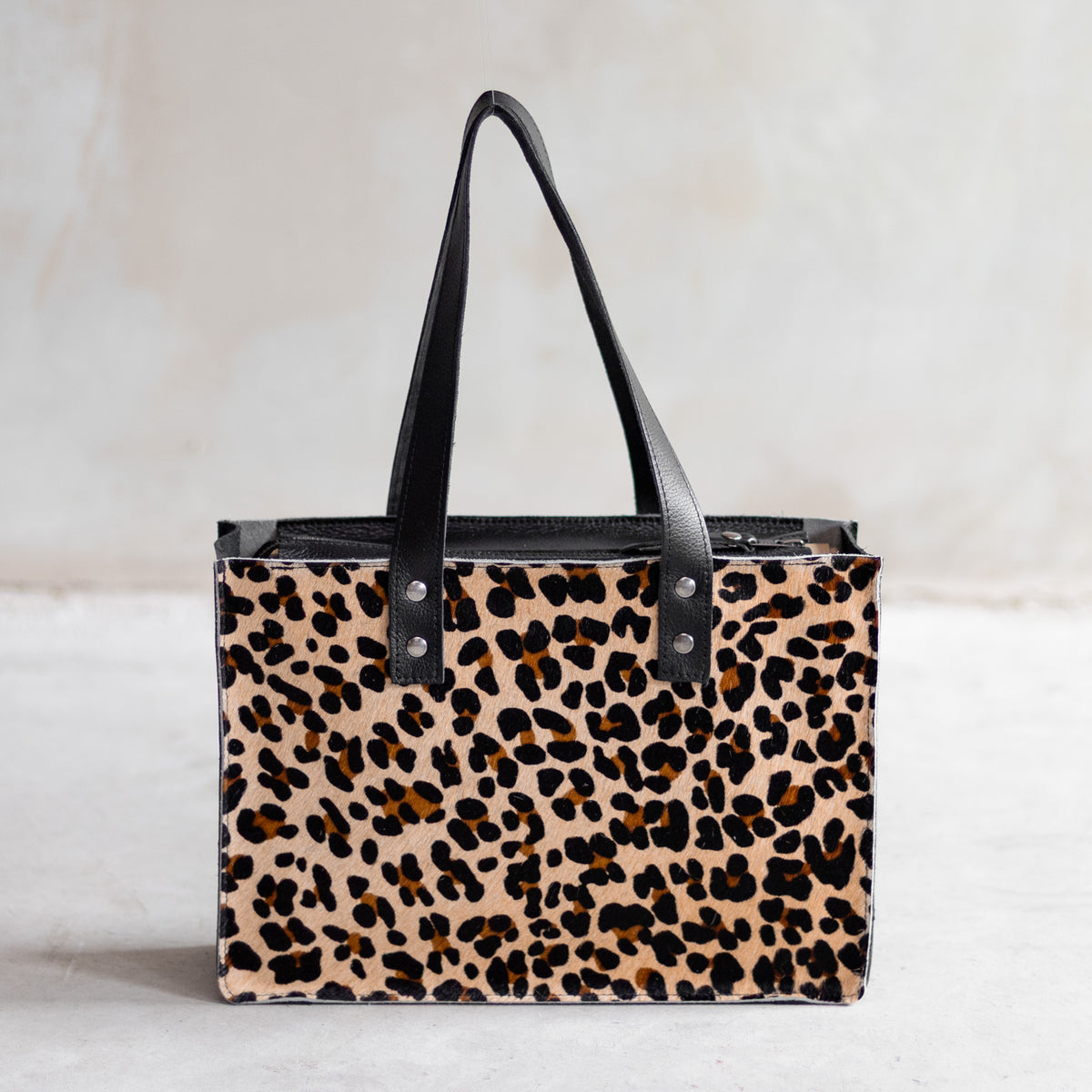 Sac à main rectangulaire en cuir noir et peau de vache léopard, vu de face