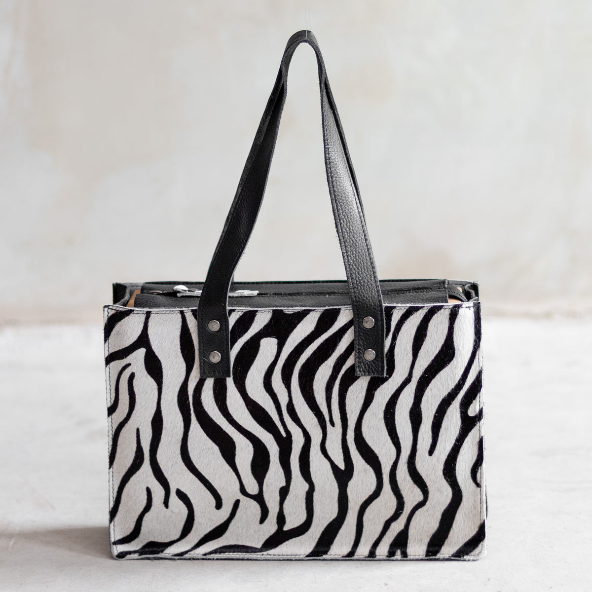 Sac à main rectangulaire en cuir noir et peau de vache zèbre, vu de face
